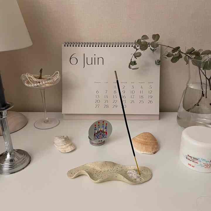 ベージュと白のトーンのテーブル上に香立てと貝殻が配置された自然な雰囲気のデスクデコ空間