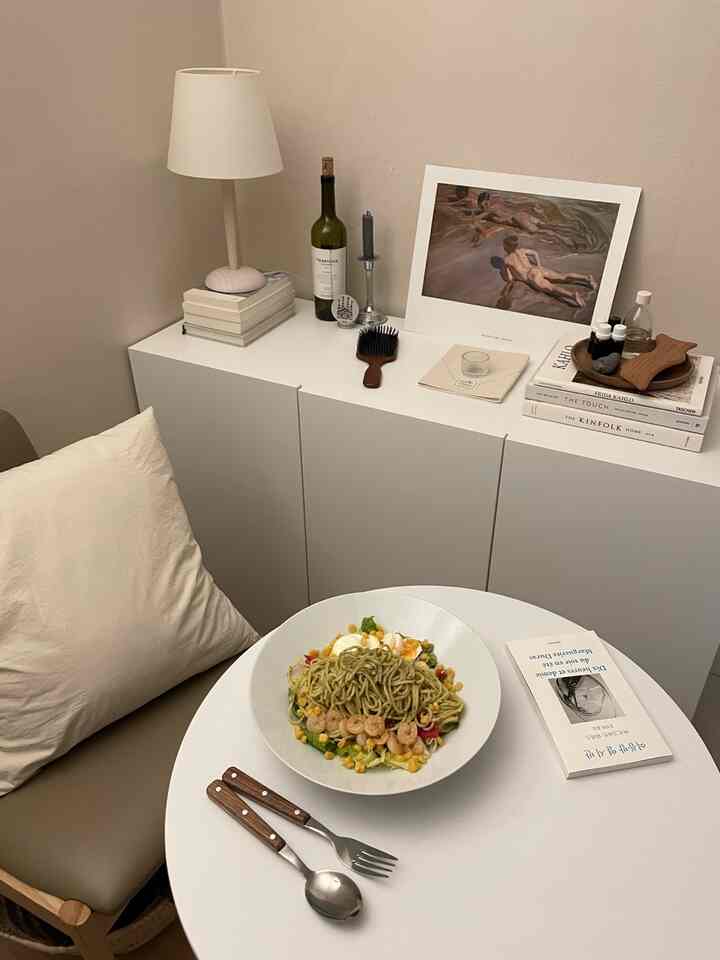 白とナチュラルカラーの狭いダイニングスペースで、折りたたみ円形テーブルとアカシア材のアクセサリーが配置された落ち着いたインテリア