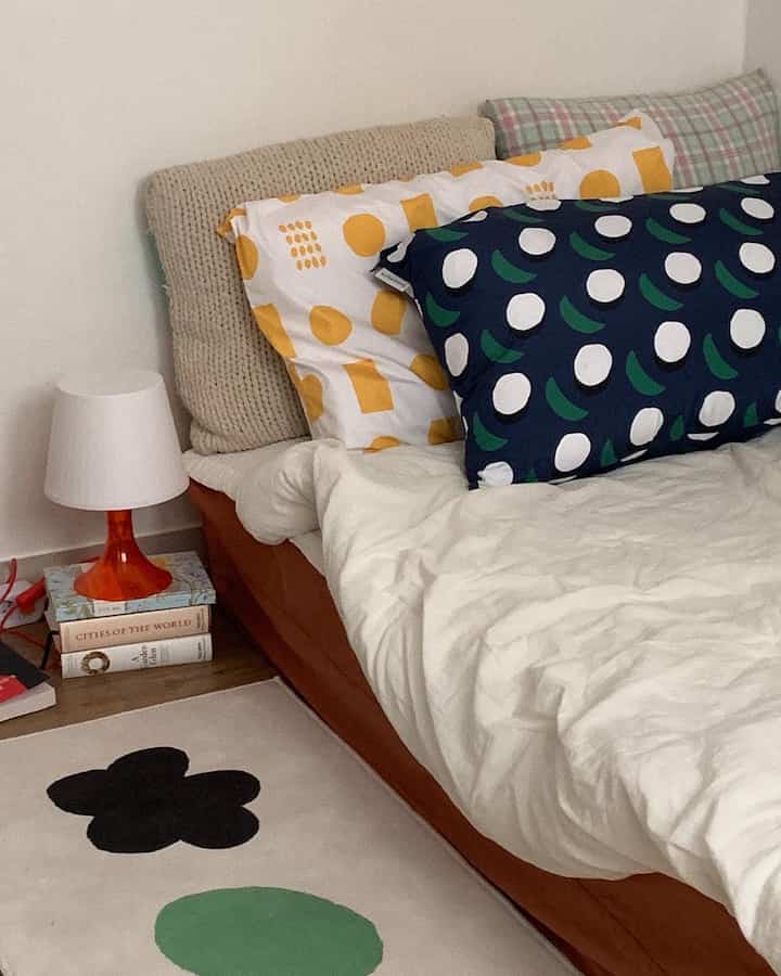 白と茶色のトーンの寝室、様々な柄の枕と寝具が配置された雰囲気のあるインテリア