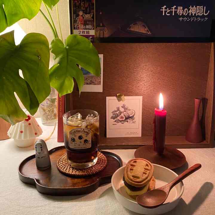 温かみのある木目調の背景とキャンドル、飲み物、植物が配置された雰囲気のあるおうちカフェ空間