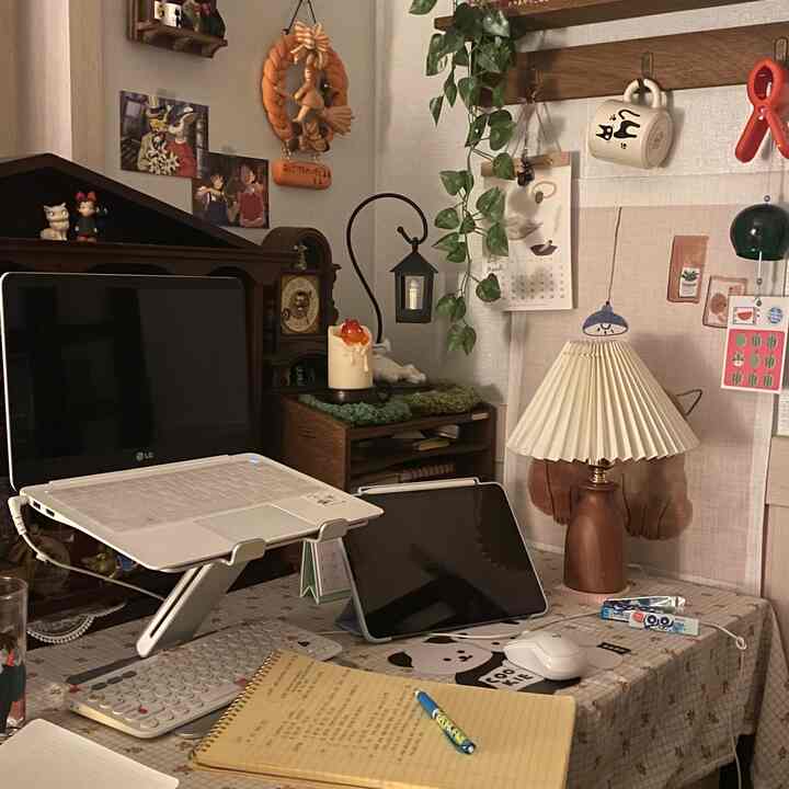 ナチュラルな色調のホームオフィス、木製棚と調節可能なアルミ製ノートパソコンスタンドが配置された居心地の良い書斎