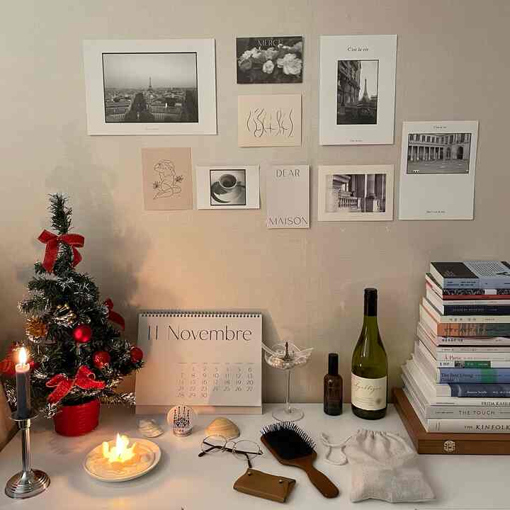 ベージュトーンの壁にミニクリスマスツリーとキャンドル、収納キャビネット、ポストカードが配された落ち着いたミニマルな北欧風インテリア