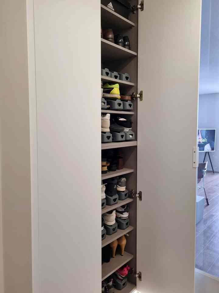 ホワイトとナチュラルトーンの調和した玄関のシューズラックが全開で、整頓された靴収納ラックが配置された清潔感のある空間