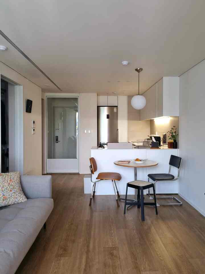 ホワイトとウッドトーンが調和した1LDKアパートのリビングと小さなダイニングスペース、モダンで清潔感のあるインテリア