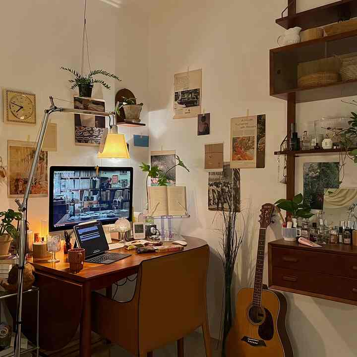 ナチュラルな木目調と温かい照明が調和した、ギターとデスクが配置された居心地の良いホームオフィス空間
