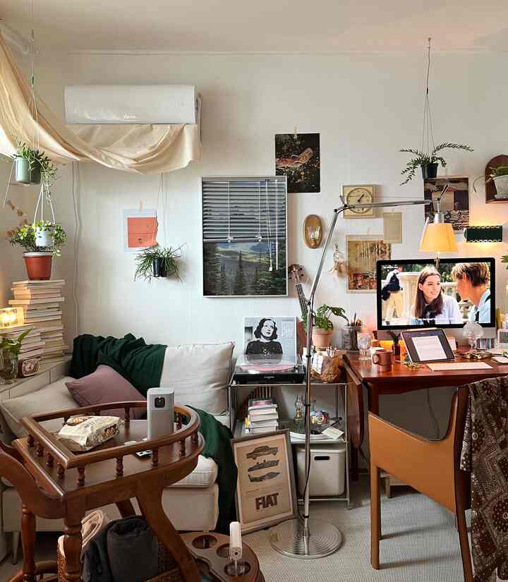 クリーム色と木目調のリビング、ヴィンテージアームチェアとデスク上のパソコンが配置された雰囲気のあるホームオフィス空間