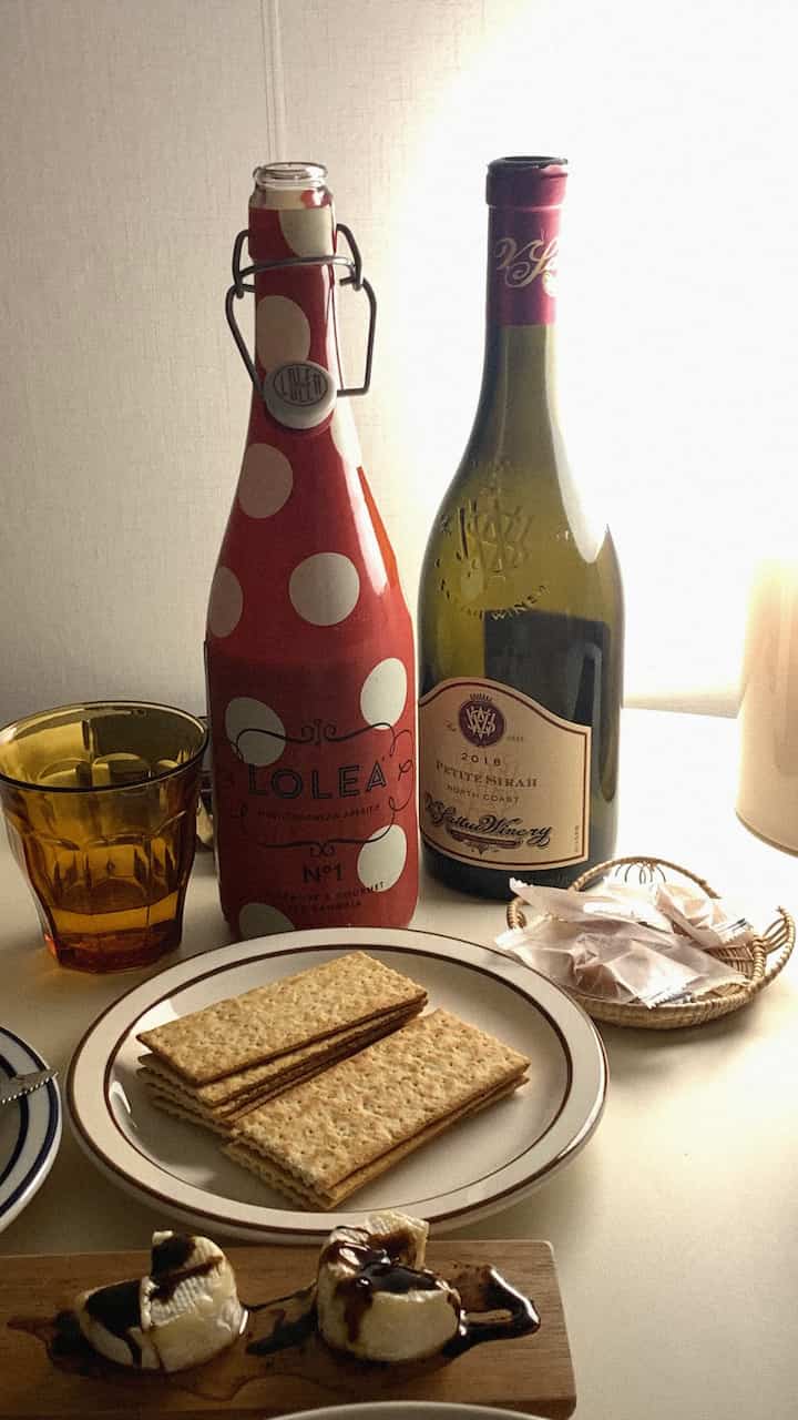 温かみのあるブラウンと透明なグラスが配置されたホームバー風のキッチン、ワインとスナックが並ぶ雰囲気のあるインテリア