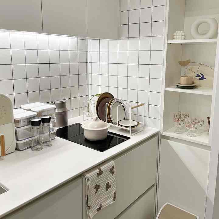 白いタイルの壁とナチュラルトーンのオブジェが配置された清潔感のあるキッチン