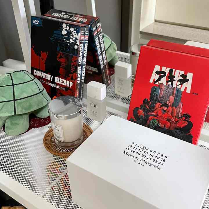 白いメッシュ棚にカウボーイビバップのDVDボックスセット、赤いアキラの本、キャンドルが整然と配置された収納スペース