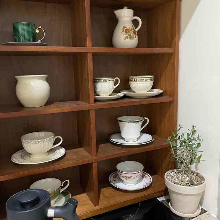 ナチュラルな雰囲気の中、ダークウッドの棚に多様なデザインのカップと皿が整然と配置された印象的な空間