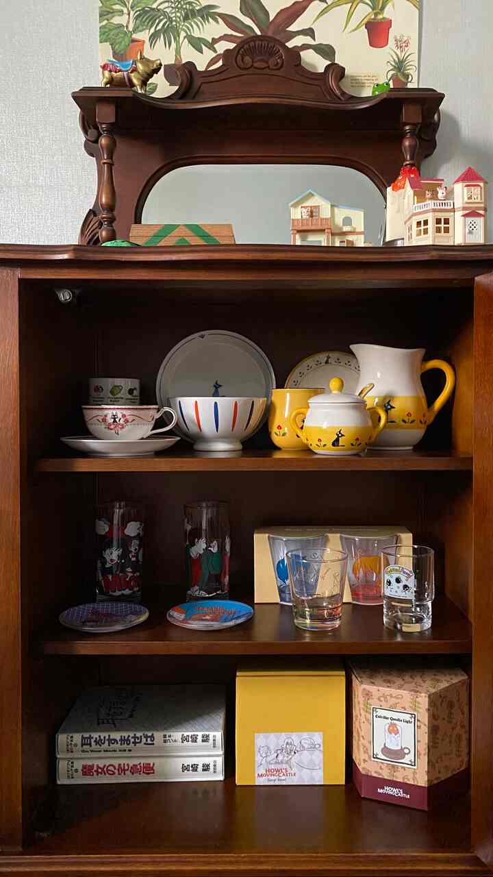 木目調のヴィンテージキャビネットに皿や様々な食器が整理された温かみのある空間