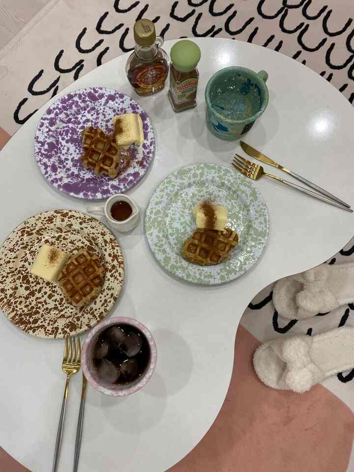 白を基調とした座卓とカラフルな皿がラグの上に配置された居心地の良いリビングスペース