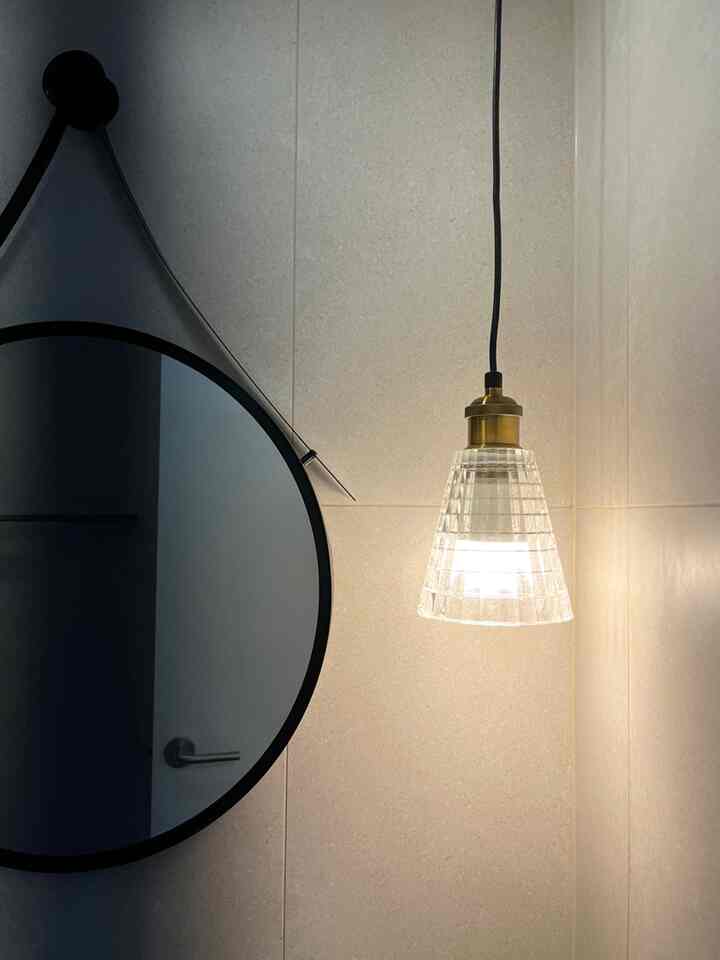 白を基調とした壁面と丸い鏡、透明なガラス製ペンダントライトが配置されたミニマルな玄関空間