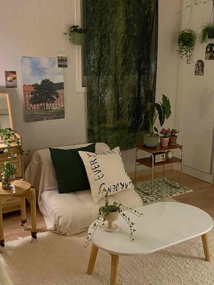 ナチュラルなグリーンと木目調が調和した小さくて居心地の良いリビング、座卓ソファと丸い座卓、植物が配置された落ち着いたインテリア