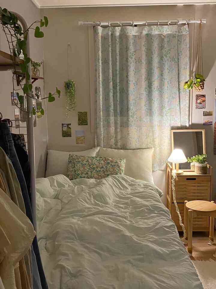 ナチュラルな色調のワンルーム寝室、大きなベッドと花柄カーテン、バンブーチェストが配置された落ち着いた空間