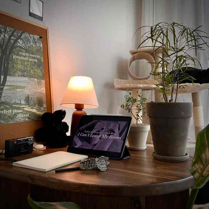 ナチュラルな色調のホームオフィス、木製デスクとテーブルランプ、キャットタワーと猫、観葉植物が配置された落ち着いた雰囲気のインテリア