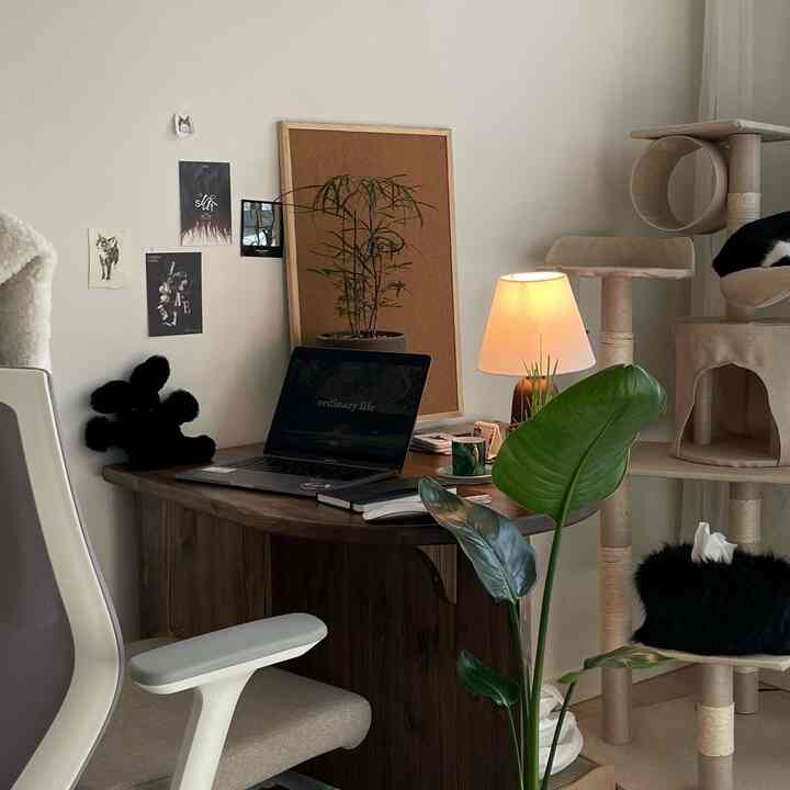 ナチュラルな木目調とホワイトが調和したホームオフィス、キャットタワーと植物が配置された雰囲気のある空間