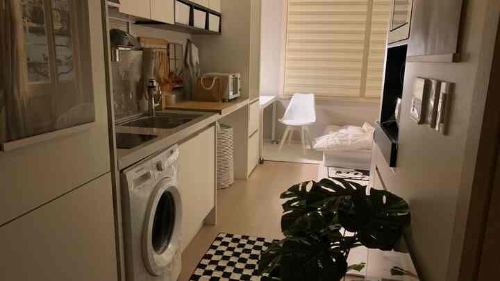 白とベージュのトーンのワンルーム、キッチンと寝室が配置された雰囲気のあるコンパクトな空間