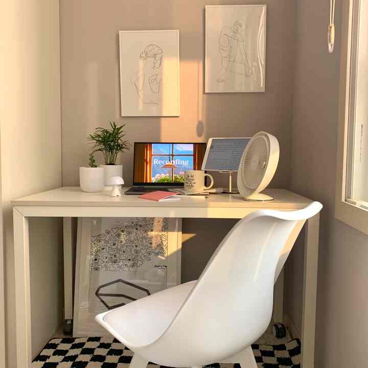 暖かな日差しが差し込む白を基調としたホームオフィス、ミニマルなアートポスターとすっきりした机が配置された空間