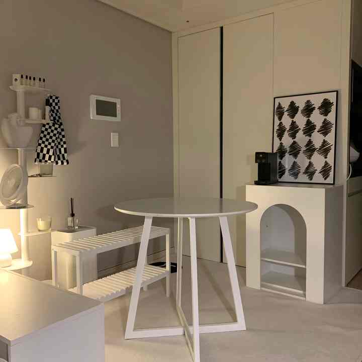 落ち着いたグレーの壁とホワイトの丸テーブル、ベンチが配置されたシンプルでモダンなダイニングスペース