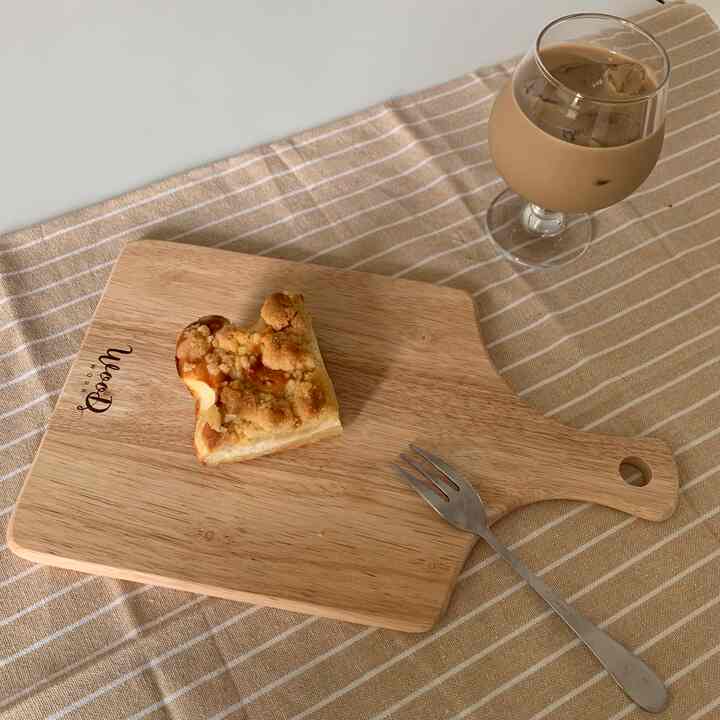 ブラウンとベージュのトーンのテーブルクロスの上に、木のまな板とカトラリーとともに整然と置かれたデザートが映える印象的な空間