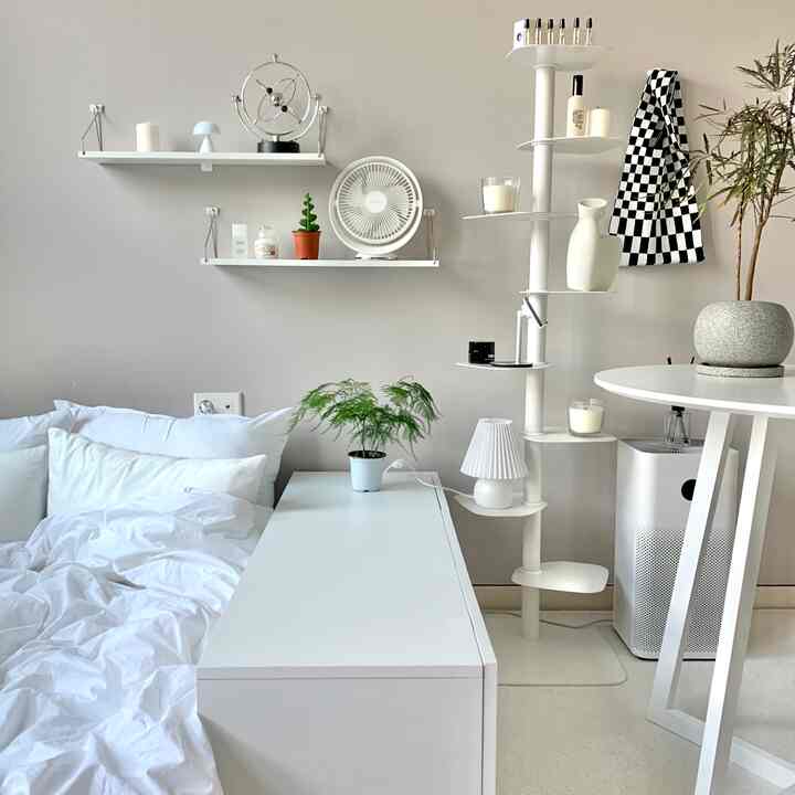 明るいホワイトとナチュラルな色調の寝室、白い寝具と壁棚、植物が配置された印象的な空間