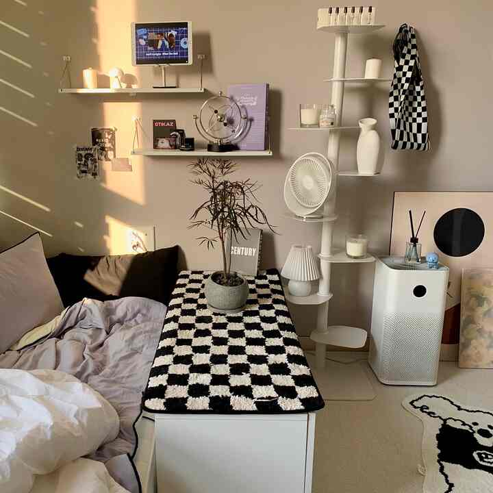 白と黒の寝室空間、ブラインドから差し込む日差しとスタイリッシュなチェッカーボードテーブルランナー、空気清浄機が配置された清潔感のあるインテリア