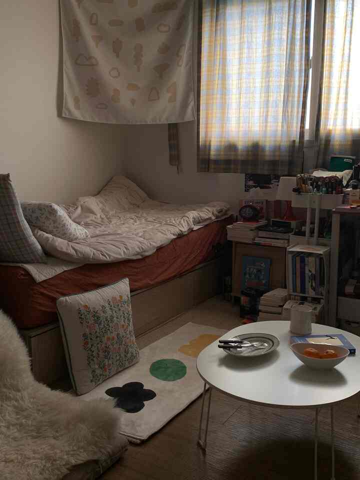 ブラウンの床とホワイトの家具が調和した狭い一人用寝室、かわいいラグとデスクが配置された居心地の良い空間