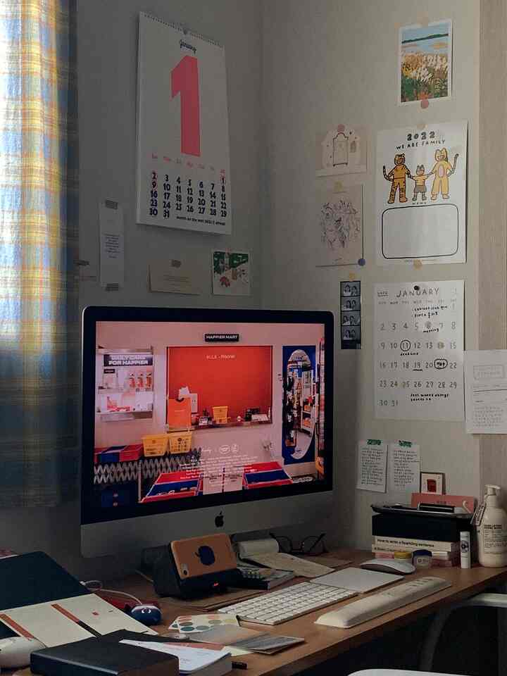 白と木目調のワンルームホームオフィス、壁に複数のカレンダーとメモが貼られた雰囲気のある作業空間