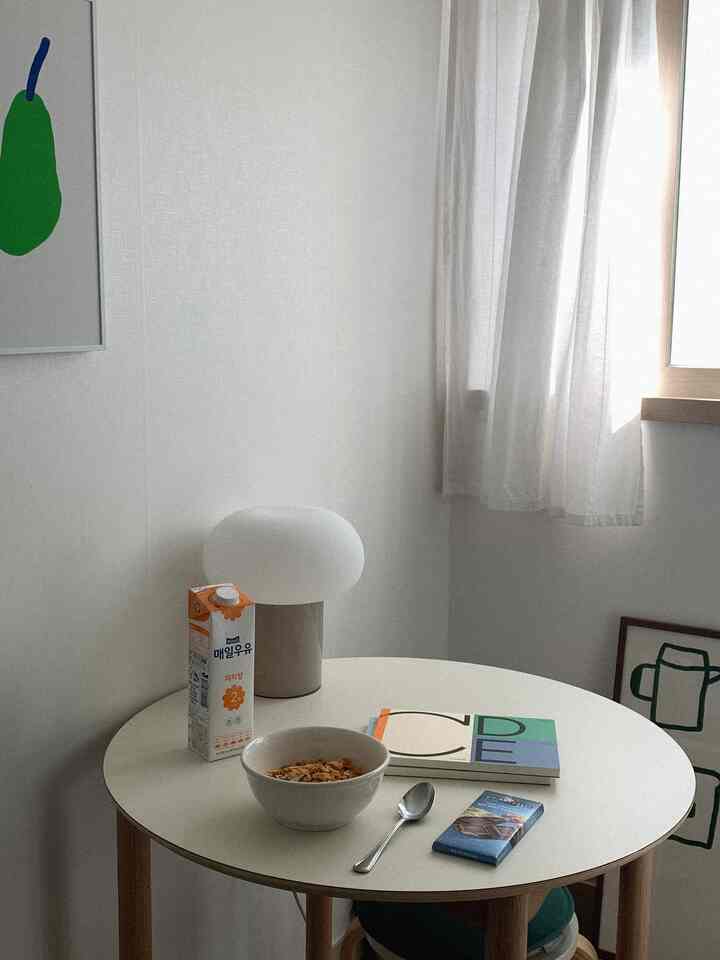 白と木目調の丸テーブルとテーブルランプが配置された、窓際の朝食スペース