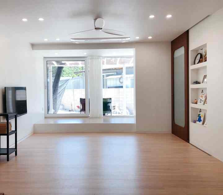 明るいホワイトとウッドトーンが調和したリビング、スッキリとしたシーリングファンと大きな窓で開放感のあるミニマルなインテリア