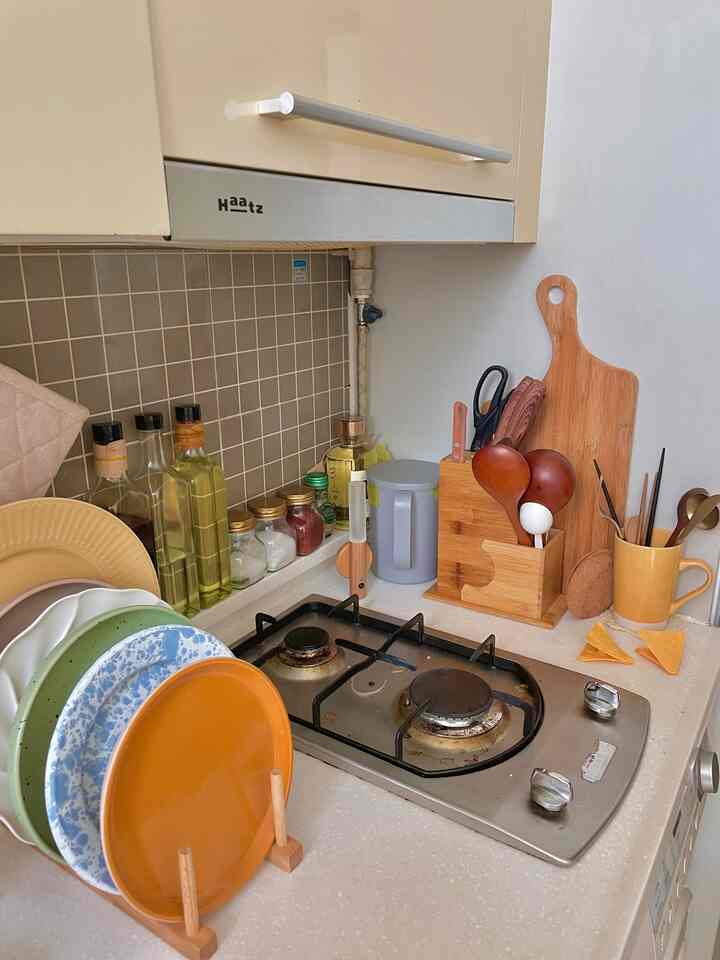 ナチュラルな色調のキッチン、整理された調理器具とカラフルな皿が清潔なカウンターに配置された雰囲気のあるインテリア