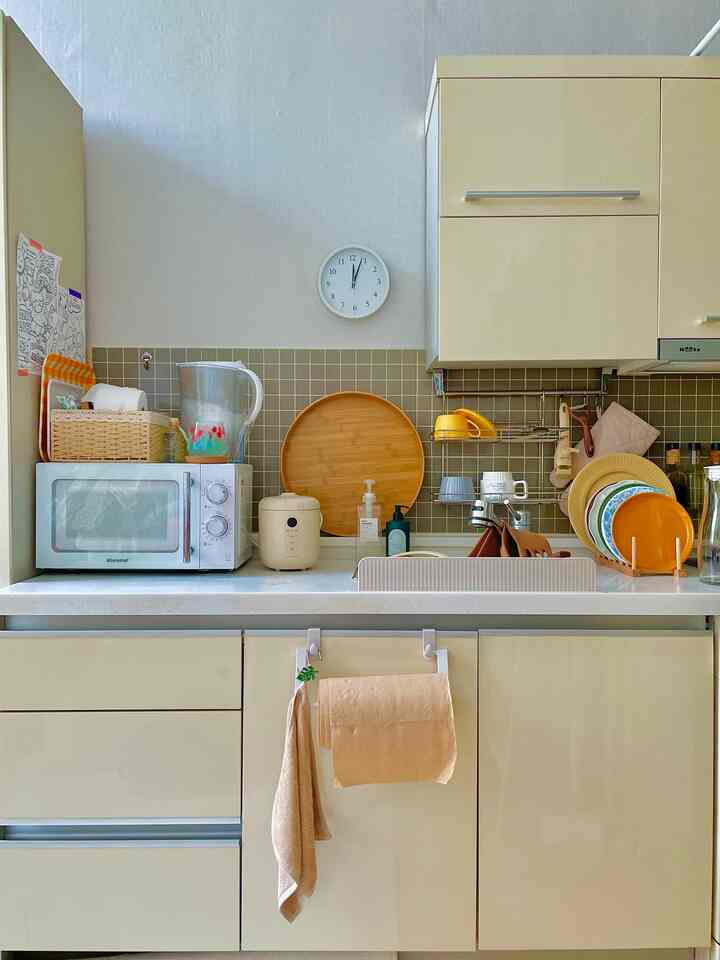 ベージュの色調のキッチン、調理器具と電子レンジ、炊飯器が整然と配置された実用的なインテリア