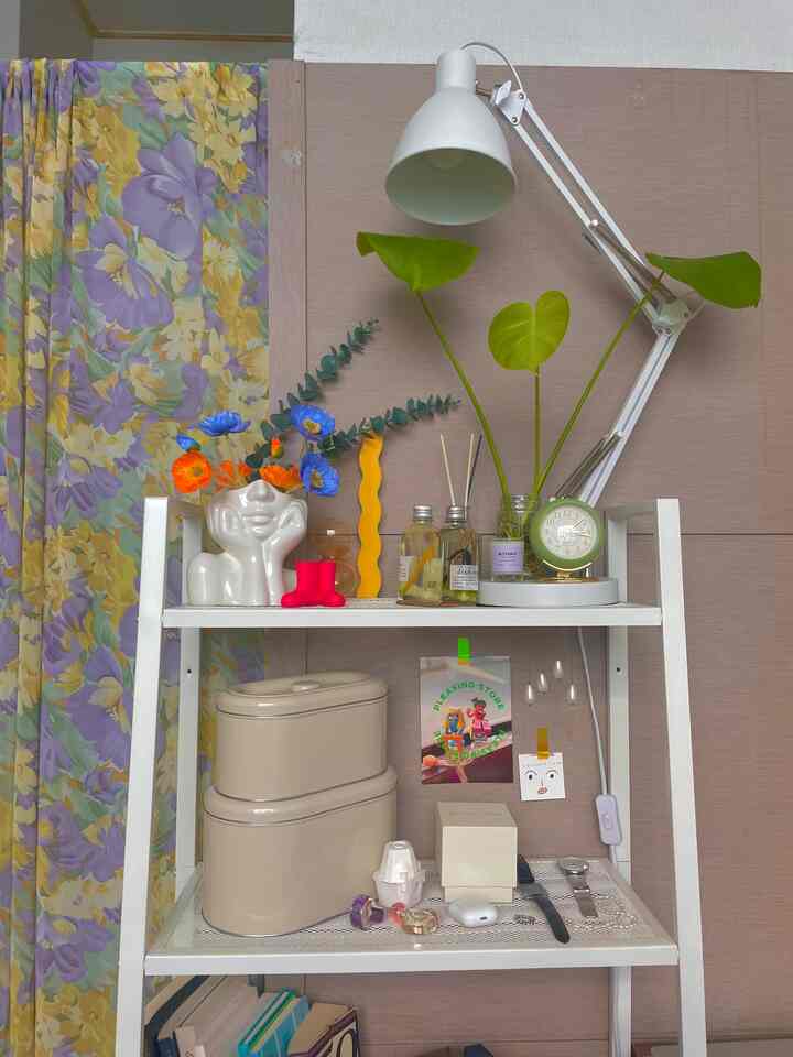 白いスチール棚と緑の時計、ランプが置かれたナチュラルな雰囲気の玄関収納スペース