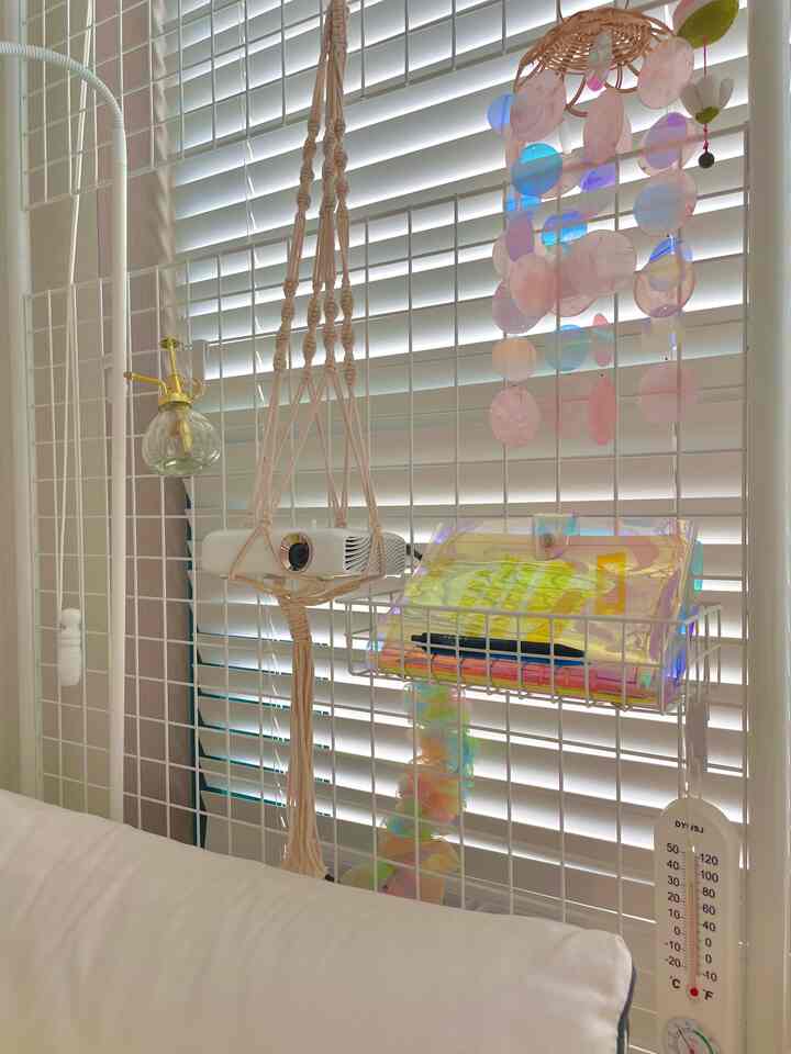 ホワイトトーンの寝室、オールホワイトのブラインドとパーティション、天井から吊るされたプロジェクターが配置された清潔感のあるインテリア