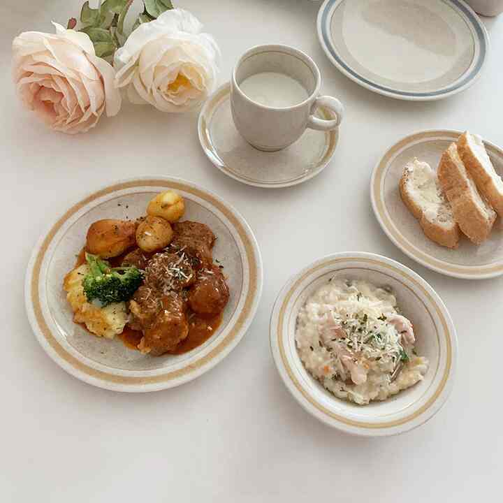 白いテーブルにブラウンの皿とカップが置かれたモダンでミニマルなおうちカフェ空間、ロマンティックローズの造花が配置されている