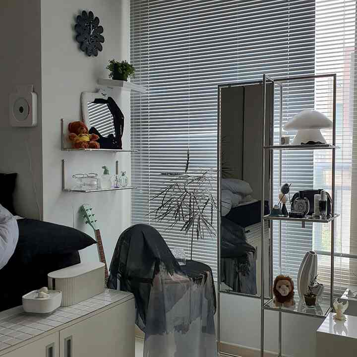 モノトーンとシルバーの調和が取れた寝室、壁棚と全身鏡、アルミブラインドが配置された雰囲気のあるインテリア