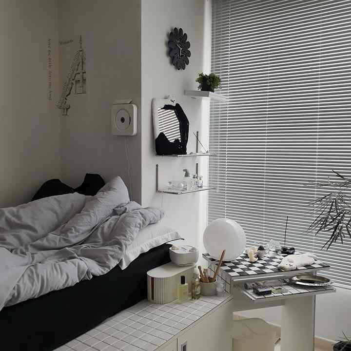 ホワイトとブラックのモノトーンの寝室、ブラインドとベッド、チェッカーボードのテーブルが配置された印象的な空間