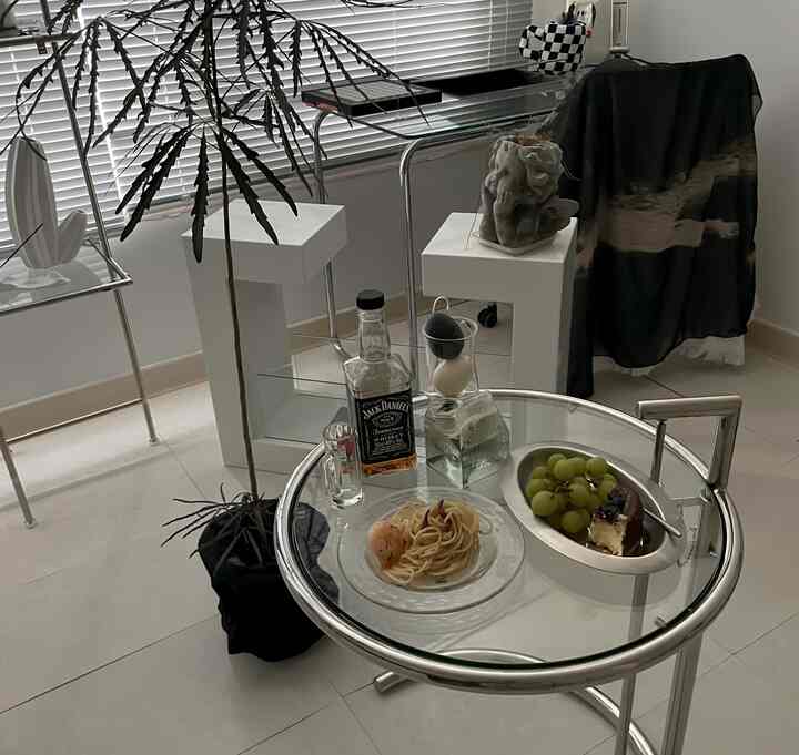 モノトーンとシルバー色調のホームカフェ空間、中央にガラスのコーヒーテーブルとモジュール家具が配置されたシンプルでモダンなインテリア