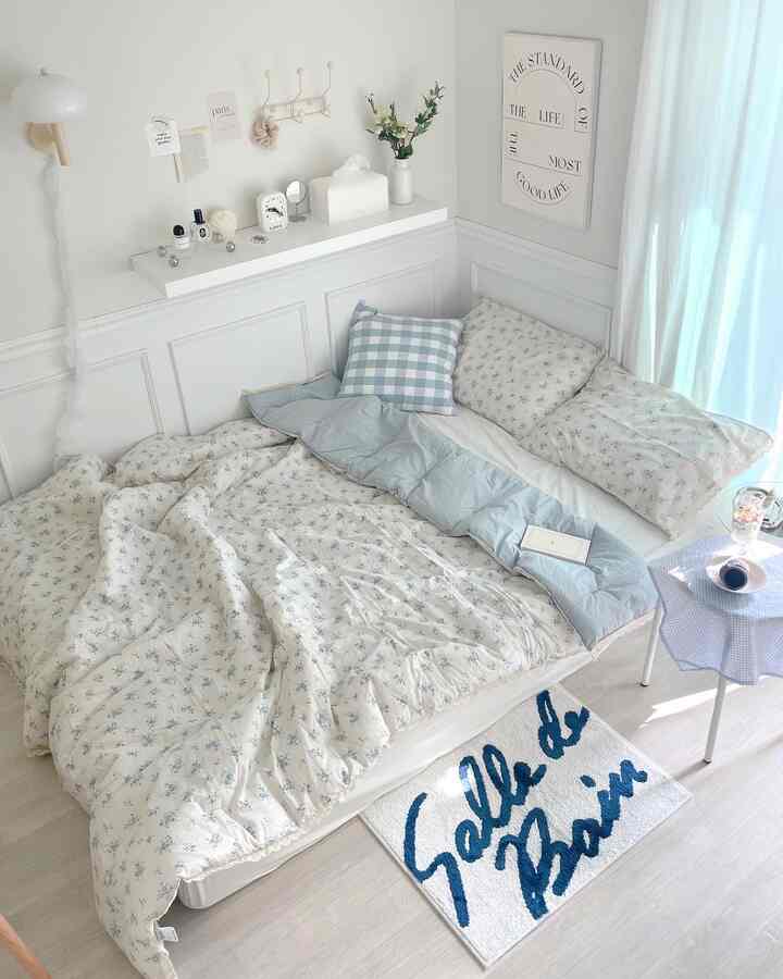 白とベージュのトーンの寝室空間、花柄の寝具とラグが調和した居心地の良いコテージスタイルのインテリア