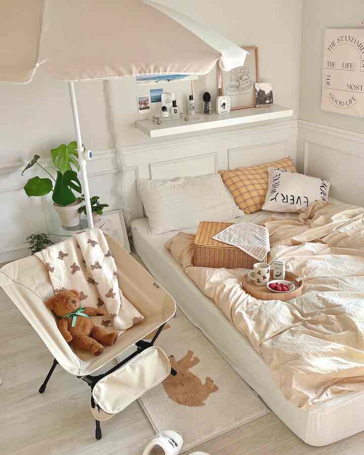 ベージュとホワイトの色調の寝室、パラソルと軽量チェア、ベッドリネンと壁棚が配置された居心地の良い空間