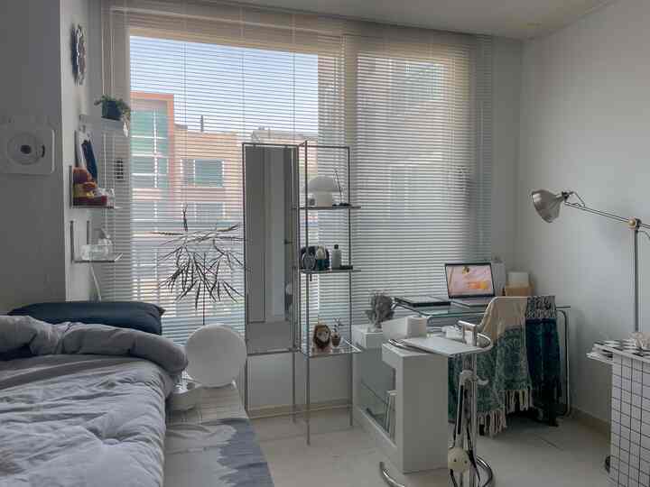 ホワイトトーンの小さな寝室、アルミニウムのブラインドとモジュール家具が配置されたモノトーンの空間