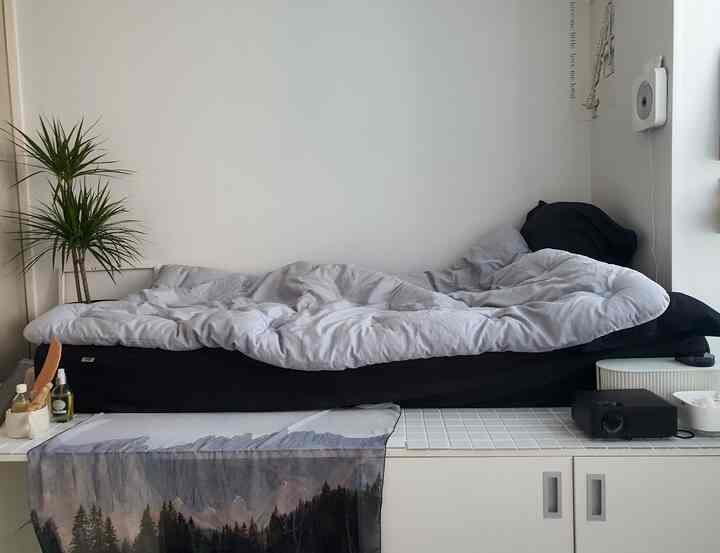 ホワイトとブラックのトーンの寝室、黒いベッドと白い掛け布団が配置されたミニマルで清潔感のあるインテリア