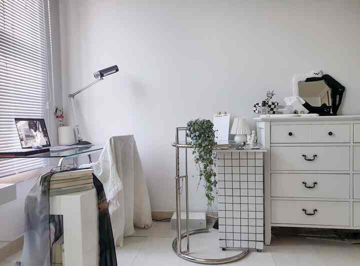 ホワイトとシルバーのトーンが印象的なシンプルな書斎、ガラスのデスクと固定されたチェストが配置された明るく清潔なインテリア