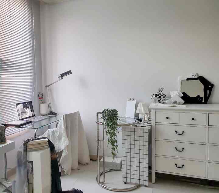 ホワイトとシルバーメタルのトーンのホームオフィス、窓辺に配置されたガラスデスクと収納チェストが配されたモノトーン空間