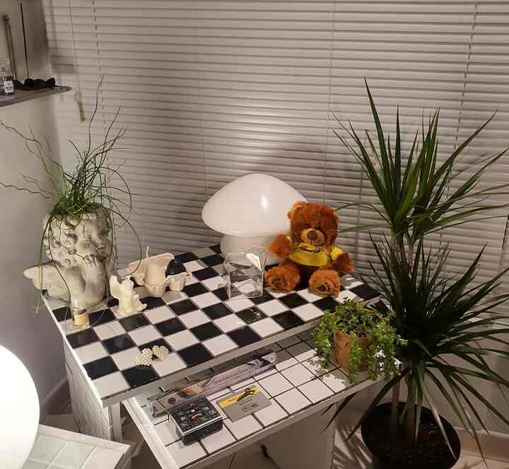 白と黒のモノトーンチェッカーボードタイルのテーブルとデスク、植物が配されたコンパクトなリフォームされた作業空間