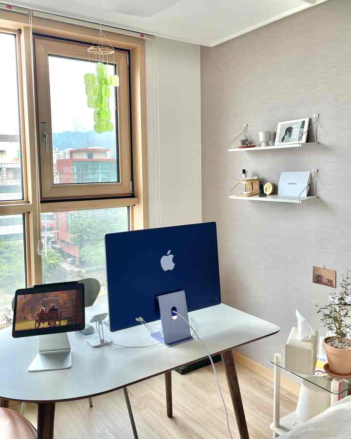 白とナチュラルカラーが調和したホームオフィス空間、半楕円形のデスクにiMacとiPadが配置された清潔感のある作業環境