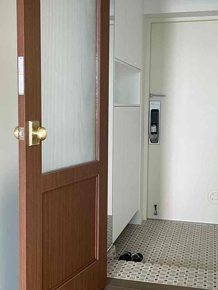 白とアイボリーの色調の玄関、シンプルなデザインのシューズラックが配置された清潔感のある空間