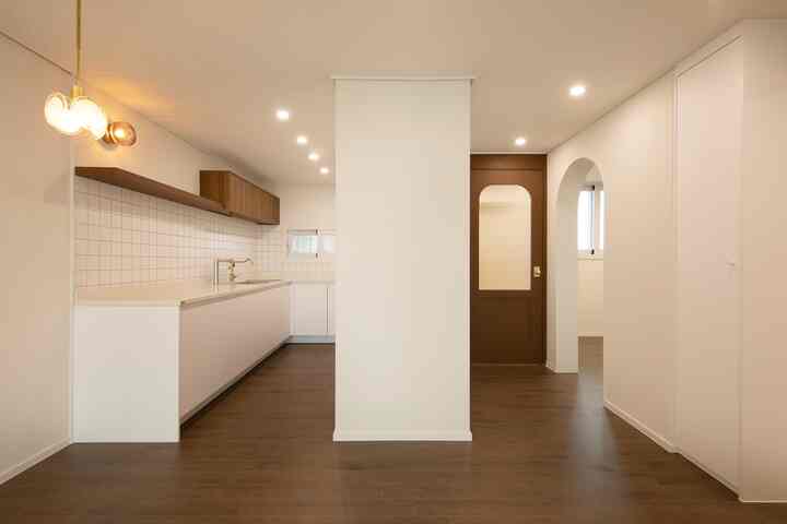 白と茶色のトーンのキッチン、シンプルモダンなスタイルで広く清潔感のあるレイアウトが印象的なインテリア