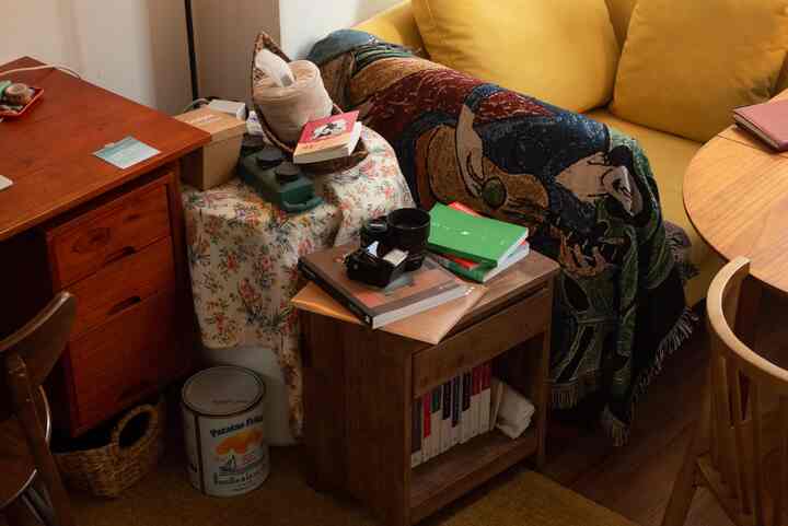 暖かい黄色とナチュラルな木目調が調和した印象的なリビング、ソファやデスク、収納用のナイトテーブルが配置された雰囲気のあるインテリア